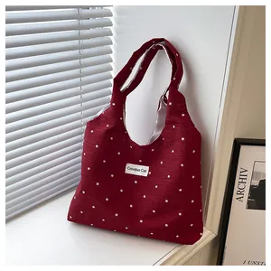 Detalle del bolso tote burdeos con lunares y etiqueta Creative Cat en tejido texturizado