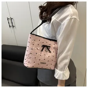 Detail of pink bucket bag with embossed texture, black bow accents and heart pendant