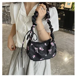 Close-up of black floral canvas shoulder bag with pink roses and ruffled handle detail