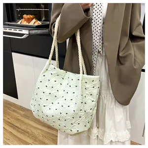 Close-up of mint green tote bag with black bow prints and thick white rope handles