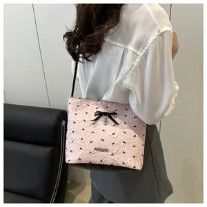 Detail view of pink tote bag with bow patterns and heart pendant shown on model