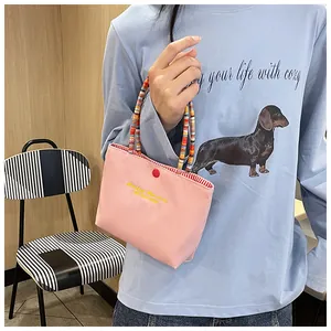 Pink canvas handbag featuring yellow Fantasy Romance embroidery and colorful beaded handle