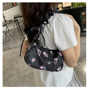 Detailed close-up of a black canvas shoulder bag featuring pink roses and bow designs