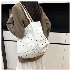 Detail of white bubble fabric tote bag with black bow patterns and cotton rope straps