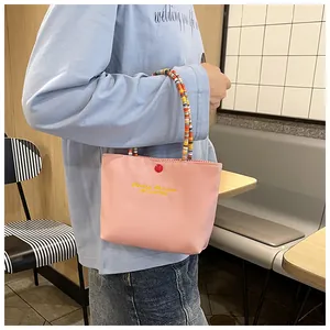 Pink waterproof nylon handbag with yellow embroidery and colorful beaded handle detail