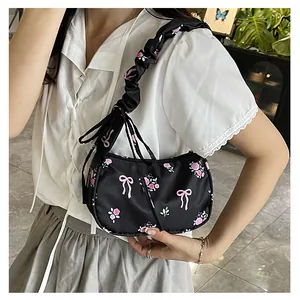 Detail of floral shoulder bag with pink bows, roses and ruffled strap in Balletcore style