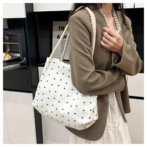 Side view of white bubble fabric tote bag with black bow patterns and rope handles