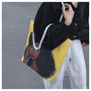Detailed shot of yellow canvas tote bag with woven rope handles and cartoon print illustration