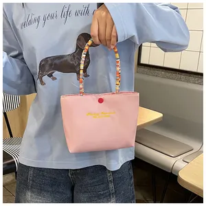 Detailed shot of pink tote bag featuring colorful beaded handle and fine embroidery