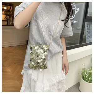 Détail d'un mini sac bandoulière à paillettes dorées avec une chaîne élégante