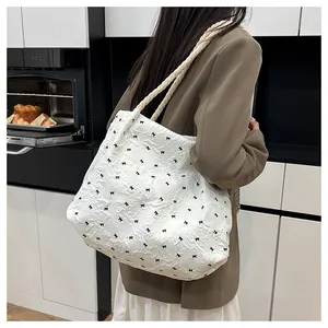Detail of white tote bag with bubble texture, black bows, and braided rope handles