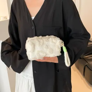 White faux shearling makeup bag with plush texture and green decorative loop handle
