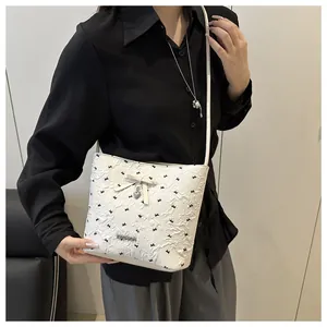 Detail of white bucket bag featuring black butterfly prints and a bow decorative charm