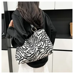 Detail view of stylish zebra print canvas tote bag with black leather shoulder straps