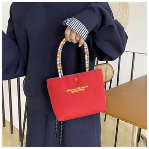 Detail of red canvas tote bag with colorful beaded handle and Fantasy Romance embroidery