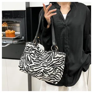 Detail of zebra print canvas tote with long black shoulder straps and metal ring buckles