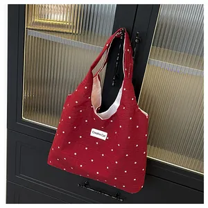 Detalle de bolso tote rojo con flores colgado de un mueble con estilo casual y elegante