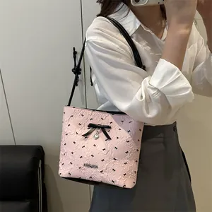 Pink textured bucket bag with black bows, silver heart pendant, and metal logo