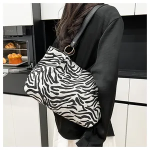 Close-up of zebra print tote bag with black leather shoulder strap and gold ring