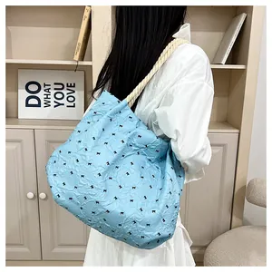 Detail of light blue pleated tote bag with black bow patterns and rope shoulder strap