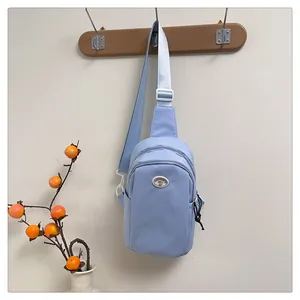 Macro detail of light blue nylon chest bag with adjustable strap and brand badge