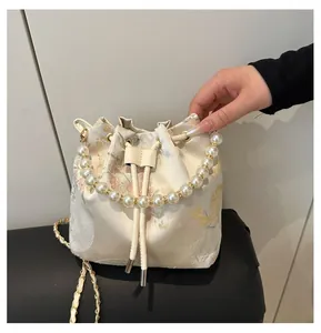 Detail of floral jacquard bucket bag with pearl handle and drawstring closure