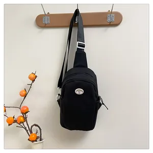 Detail of minimalist black nylon chest bag with adjustable strap and oval logo patch