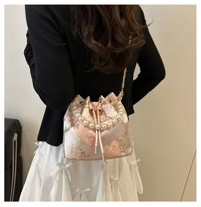 Detailed back view of a pink embroidered bucket bag with pearl handle and chain strap