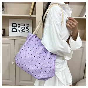 Detail of light purple tote bag with bow print and cream rope shoulder strap