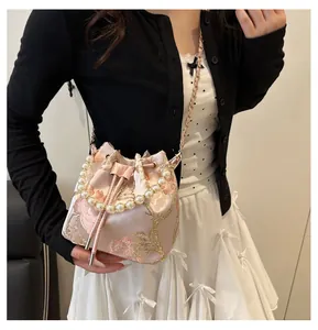 Detailed embroidery and pearl handle on pink satin bucket bag with floral patterns
