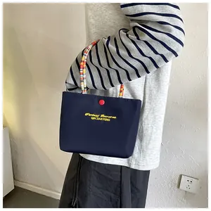 Detail of navy tote bag with yellow embroidery and colorful patterned handles