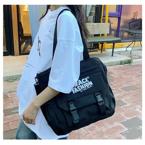 Détail d'un grand sac bandoulière en toile noire avec deux poches à boucle à l'avant