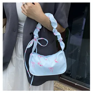 Detail of light blue floral canvas bag with ruffled strap and ribbon accents on a model