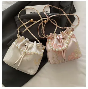 Close-up of vintage embroidered bucket bags with pearl handles and metallic gold chain straps
