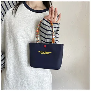 Detail of navy canvas handbag with Fantasy Romance embroidery and colorful beaded handle
