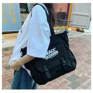 Vue latérale du grand sac bandoulière en toile noire porté par un mannequin avec boucle
