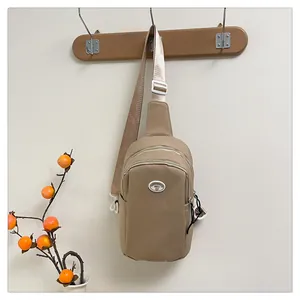 Detail of khaki nylon chest bag showing zipper compartments and adjustable strap