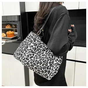 Close-up of zebra pattern canvas tote with black leather straps and gold metal rings