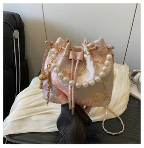 Detail of pink embroidered bucket bag with pearl handle and golden floral patterns