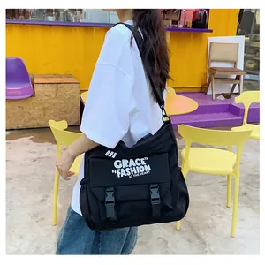 Détail du sac bandoulière en toile noire avec boucles de sécurité et imprimé tendance