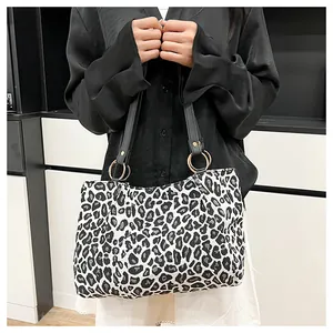 Detail of zebra print tote bag with black shoulder straps and gold metal ring connectors