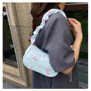 Detail of light blue floral shoulder bag featuring pink roses and ruffled strap design
