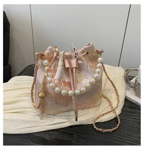 Detail of pink jacquard bucket bag with gold floral embroidery and pearl handle