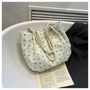 Close-up of mint green tote bag with black bow embroidery and woven rope handles