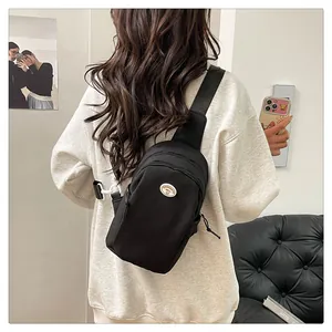 Rear view of a black nylon chest bag worn by a model in a minimalist cozy setting