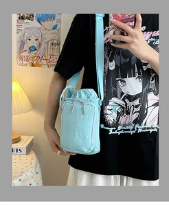 Lichtblauwe nylon mini crossbody tas met trekkoord sluiting gedragen op de schouder