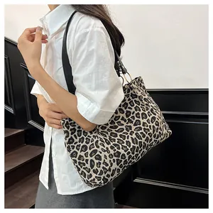 Macro detail of leopard print tote bag with black leather straps and gold metal rings