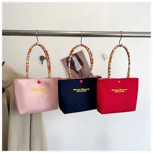 Detailed embroidery and colorful striped handles on pink, blue, and red nylon handbags
