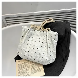 Detail of white wrinkled tote bag featuring black bow patterns and rope handles