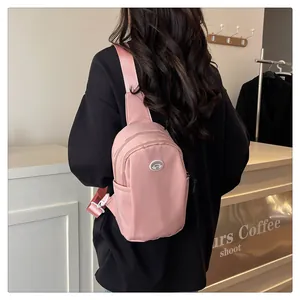Rear view of a soft pink waterproof nylon chest bag on model with adjustable straps